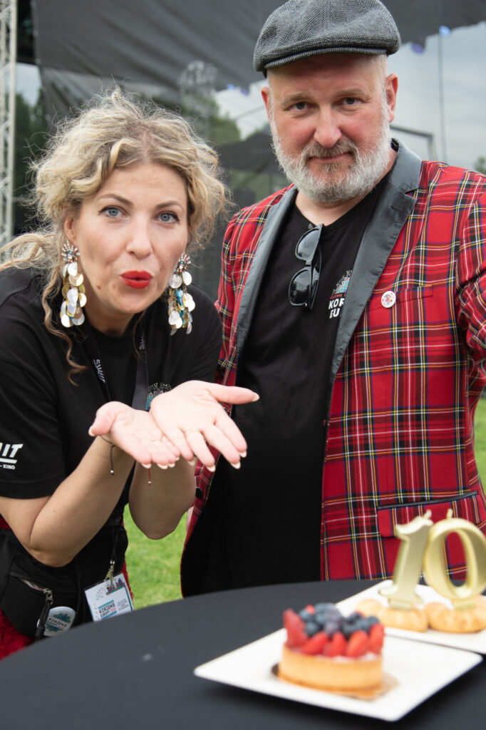 Zdjęcia z Festowalu KOrzenie Europy. Na zdjęciach widoczni są artyści na scenie, prowadzący koncert , publiczność i otoczenie koncertu - Park Bródnowski.