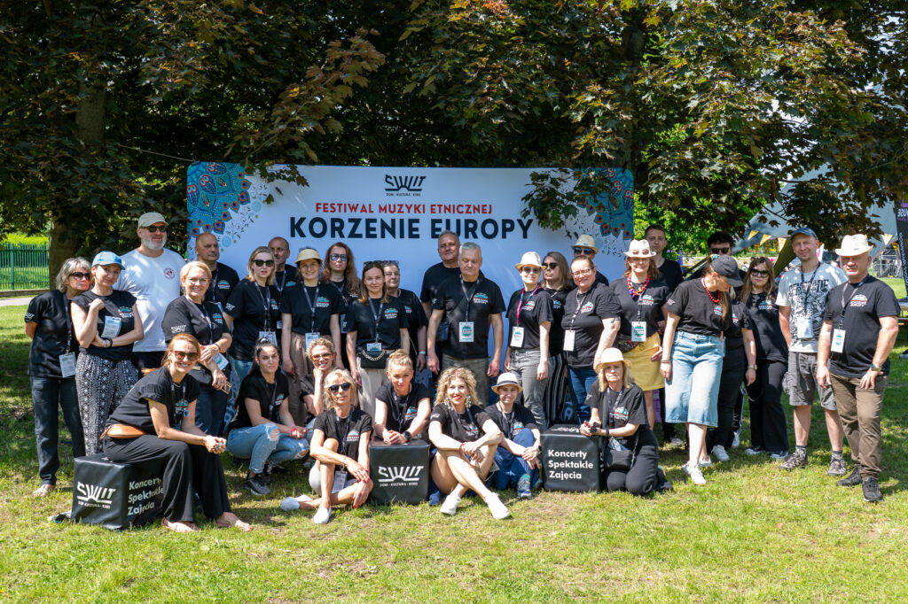 Zdjęcia z Festowalu KOrzenie Europy. Na zdjęciach widoczni są artyści na scenie, prowadzący koncert , publiczność i otoczenie koncertu - Park Bródnowski.