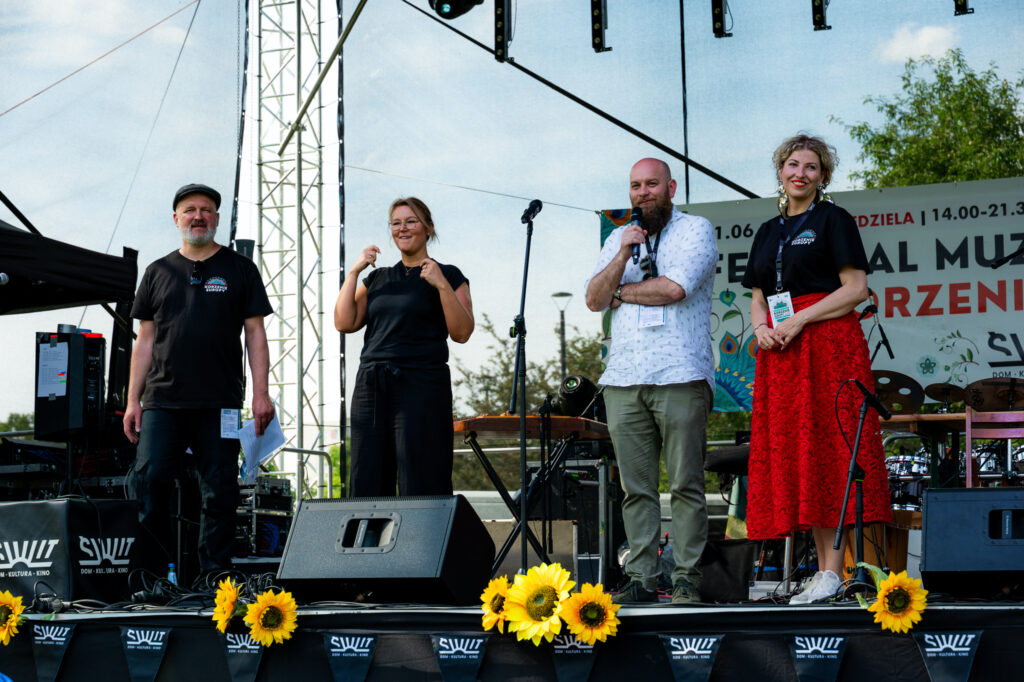 Zdjęcia z Festowalu KOrzenie Europy. Na zdjęciach widoczni są artyści na scenie, prowadzący koncert , publiczność i otoczenie koncertu - Park Bródnowski.