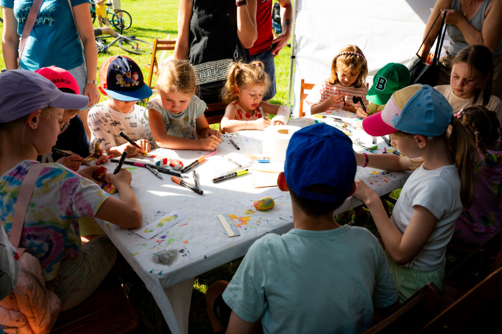 Zdjęcia z Festowalu KOrzenie Europy. Na zdjęciach widoczni są artyści na scenie, prowadzący koncert , publiczność i otoczenie koncertu - Park Bródnowski.