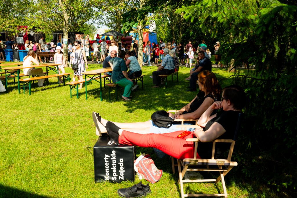 Zdjęcia z Festowalu KOrzenie Europy. Na zdjęciach widoczni są artyści na scenie, prowadzący koncert , publiczność i otoczenie koncertu - Park Bródnowski.