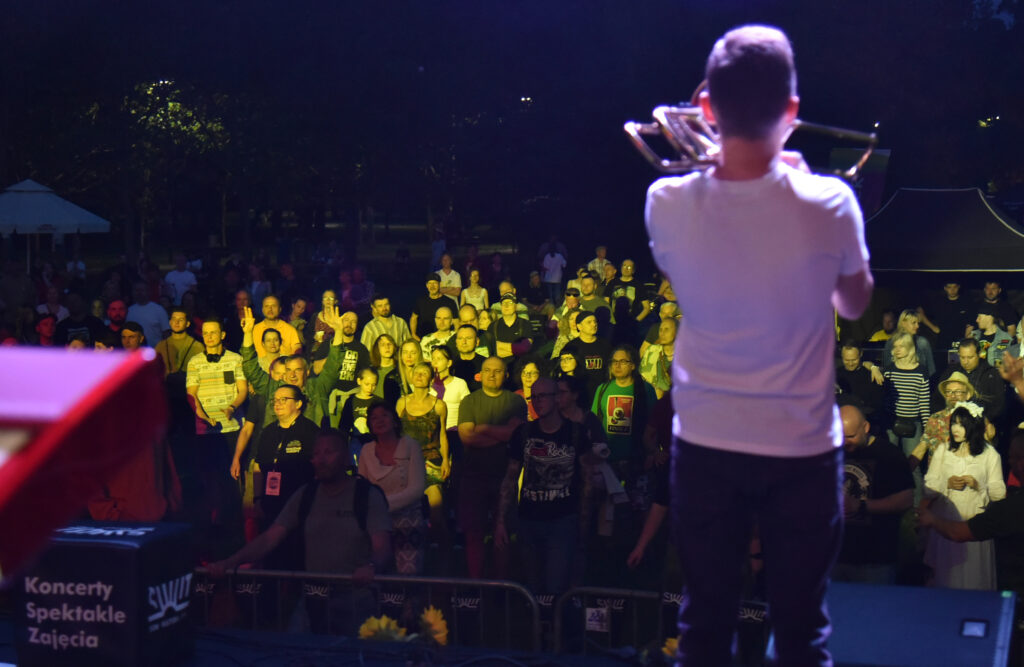 Zdjęcia z Festowalu KOrzenie Europy. Na zdjęciach widoczni są artyści na scenie, prowadzący koncert , publiczność i otoczenie koncertu - Park Bródnowski.