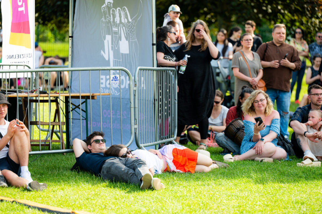 Zdjęcia z Festowalu KOrzenie Europy. Na zdjęciach widoczni są artyści na scenie, prowadzący koncert , publiczność i otoczenie koncertu - Park Bródnowski.