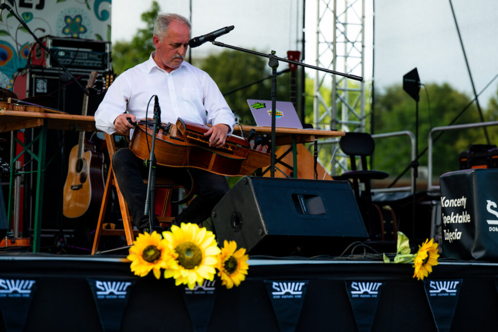 Zdjęcia z Festowalu KOrzenie Europy. Na zdjęciach widoczni są artyści na scenie, prowadzący koncert , publiczność i otoczenie koncertu - Park Bródnowski.
