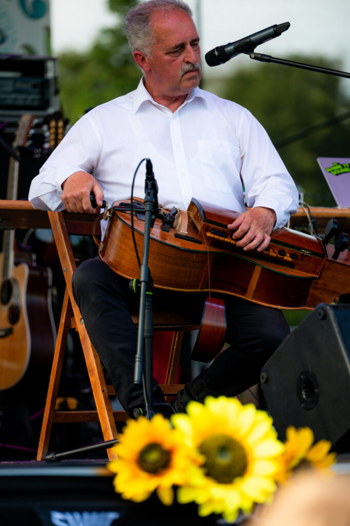 Zdjęcia z Festowalu KOrzenie Europy. Na zdjęciach widoczni są artyści na scenie, prowadzący koncert , publiczność i otoczenie koncertu - Park Bródnowski.