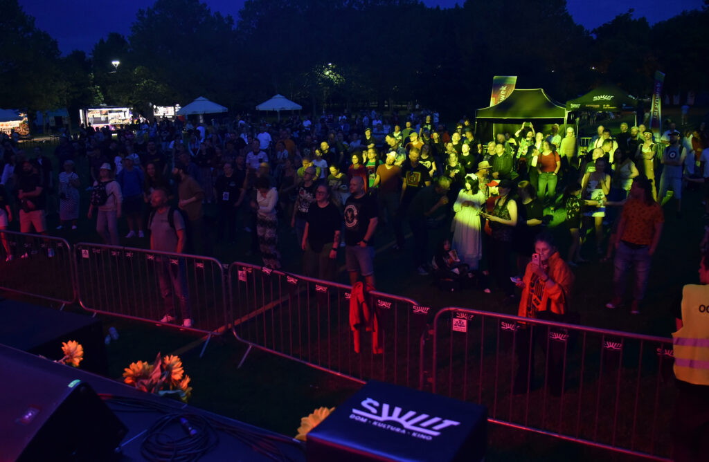 Zdjęcia z Festowalu KOrzenie Europy. Na zdjęciach widoczni są artyści na scenie, prowadzący koncert , publiczność i otoczenie koncertu - Park Bródnowski.