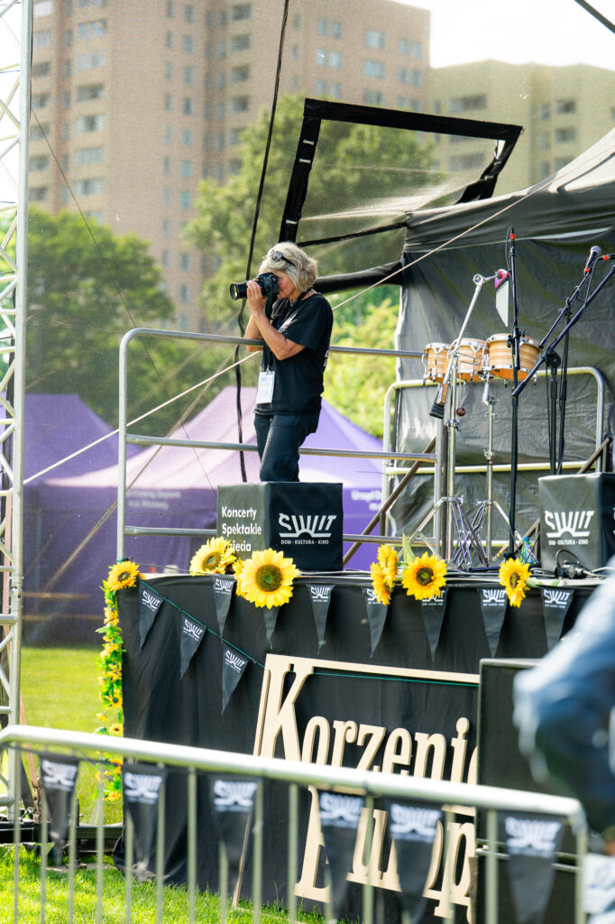 Zdjęcia z Festowalu KOrzenie Europy. Na zdjęciach widoczni są artyści na scenie, prowadzący koncert , publiczność i otoczenie koncertu - Park Bródnowski.
