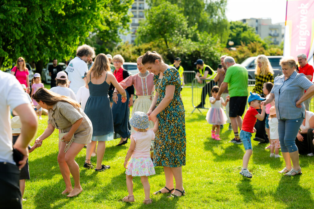 Zdjęcia z Festowalu KOrzenie Europy. Na zdjęciach widoczni są artyści na scenie, prowadzący koncert , publiczność i otoczenie koncertu - Park Bródnowski.