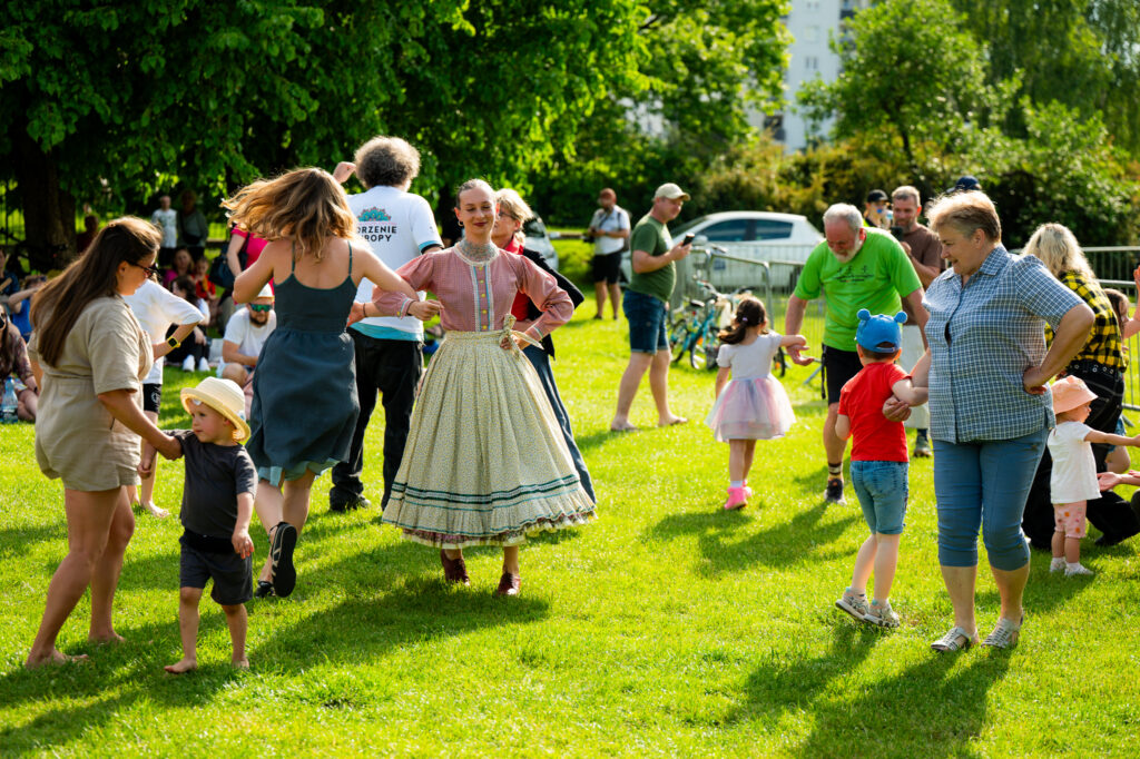 Zdjęcia z Festowalu KOrzenie Europy. Na zdjęciach widoczni są artyści na scenie, prowadzący koncert , publiczność i otoczenie koncertu - Park Bródnowski.