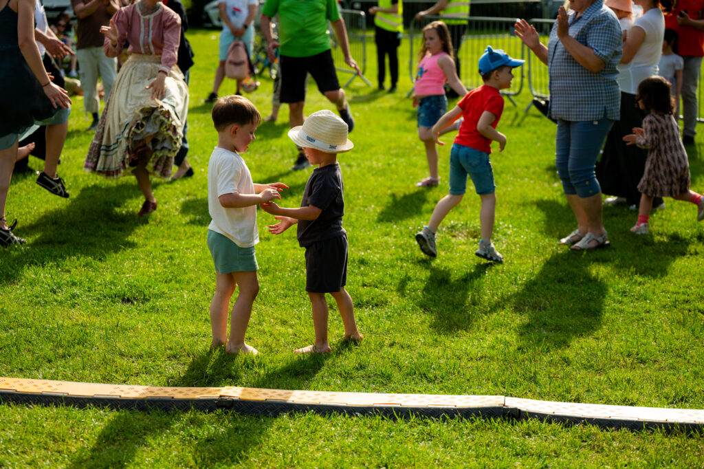 Zdjęcia z Festowalu KOrzenie Europy. Na zdjęciach widoczni są artyści na scenie, prowadzący koncert , publiczność i otoczenie koncertu - Park Bródnowski.