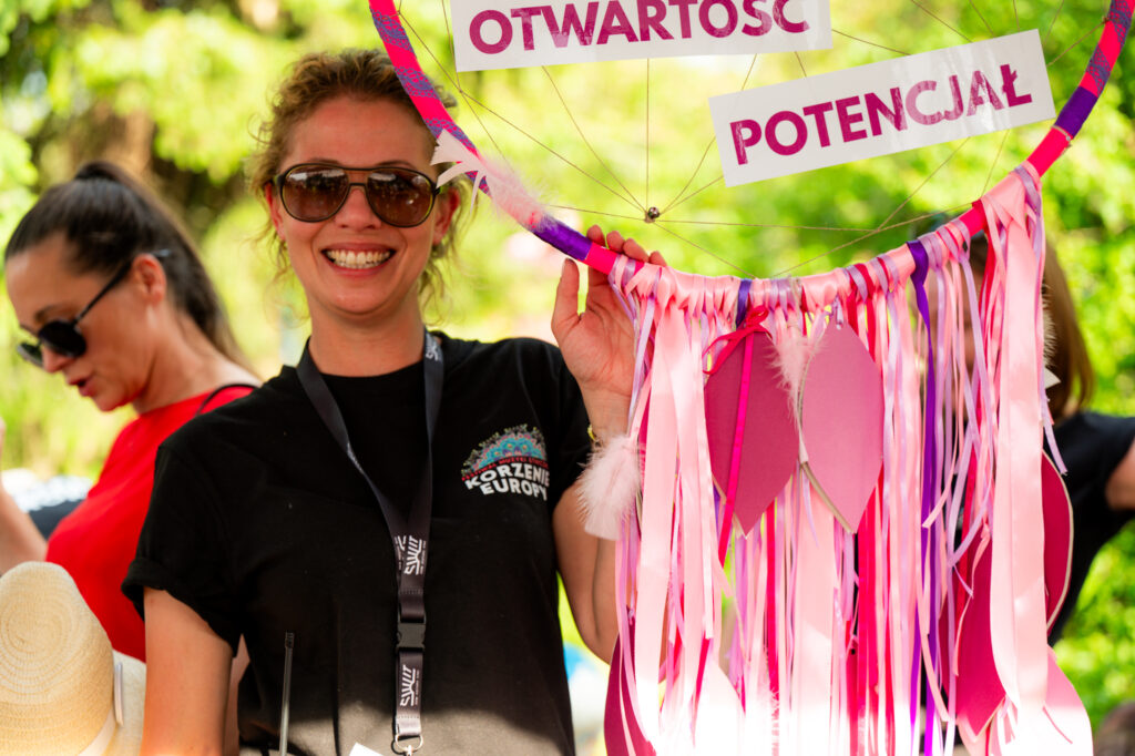 Zdjęcia z Festowalu KOrzenie Europy. Na zdjęciach widoczni są artyści na scenie, prowadzący koncert , publiczność i otoczenie koncertu - Park Bródnowski.