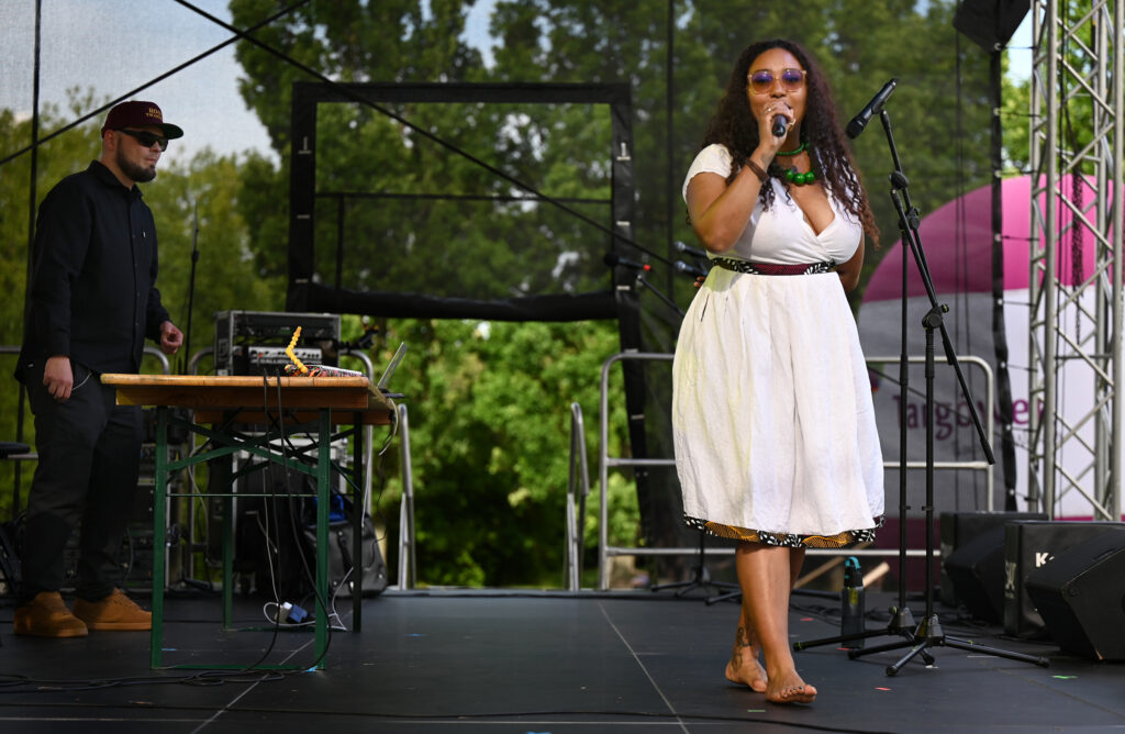 Zdjęcia z Festowalu KOrzenie Europy. Na zdjęciach widoczni są artyści na scenie, prowadzący koncert , publiczność i otoczenie koncertu - Park Bródnowski.