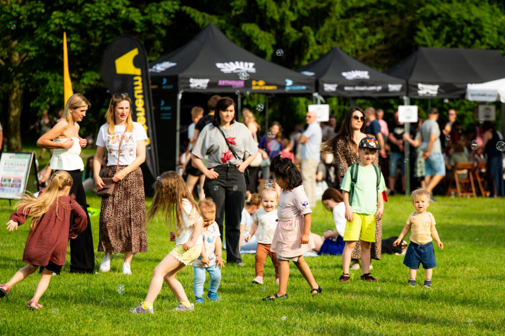 Zdjęcia z Festowalu KOrzenie Europy. Na zdjęciach widoczni są artyści na scenie, prowadzący koncert , publiczność i otoczenie koncertu - Park Bródnowski.