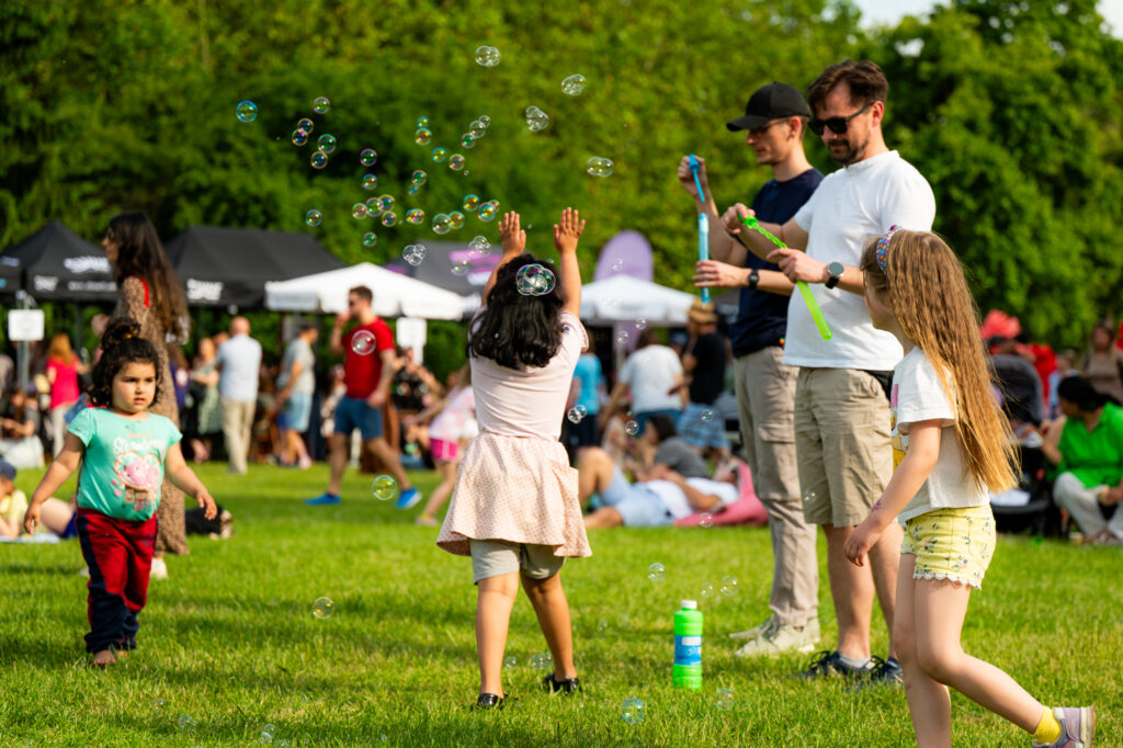 Zdjęcia z Festowalu KOrzenie Europy. Na zdjęciach widoczni są artyści na scenie, prowadzący koncert , publiczność i otoczenie koncertu - Park Bródnowski.