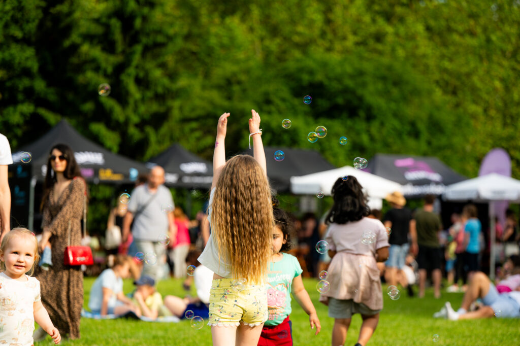 Zdjęcia z Festowalu KOrzenie Europy. Na zdjęciach widoczni są artyści na scenie, prowadzący koncert , publiczność i otoczenie koncertu - Park Bródnowski.