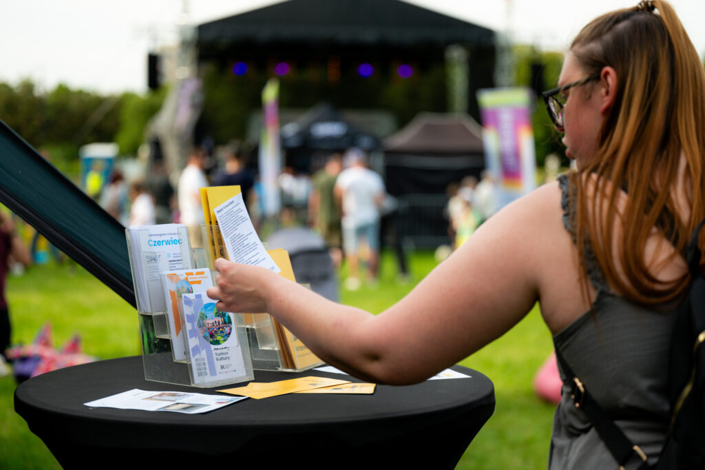 Zdjęcia z Festowalu KOrzenie Europy. Na zdjęciach widoczni są artyści na scenie, prowadzący koncert , publiczność i otoczenie koncertu - Park Bródnowski.