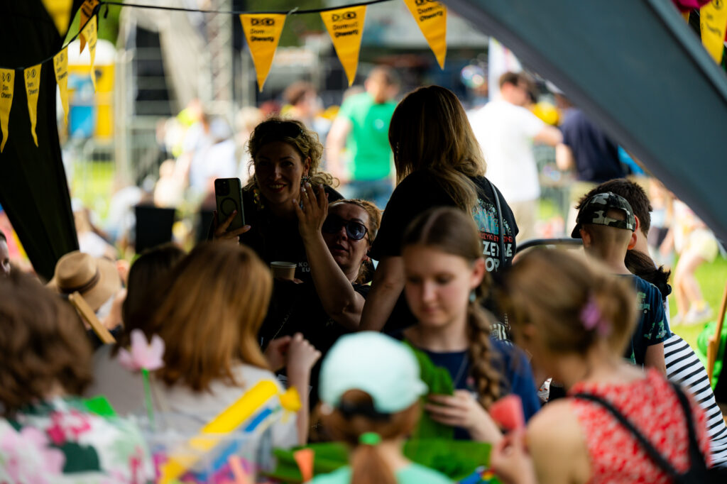 Zdjęcia z Festowalu KOrzenie Europy. Na zdjęciach widoczni są artyści na scenie, prowadzący koncert , publiczność i otoczenie koncertu - Park Bródnowski.