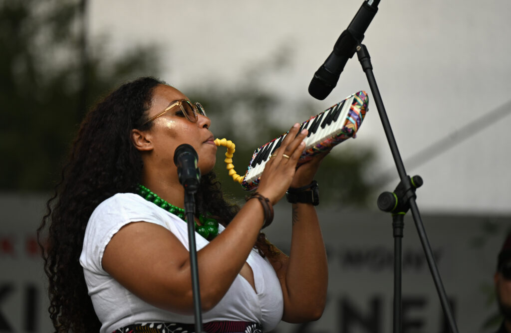 Zdjęcia z Festowalu KOrzenie Europy. Na zdjęciach widoczni są artyści na scenie, prowadzący koncert , publiczność i otoczenie koncertu - Park Bródnowski.