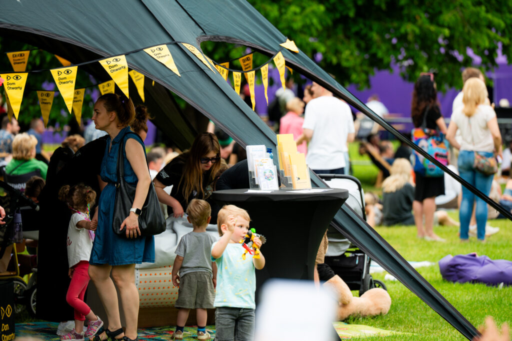 Zdjęcia z Festowalu KOrzenie Europy. Na zdjęciach widoczni są artyści na scenie, prowadzący koncert , publiczność i otoczenie koncertu - Park Bródnowski.