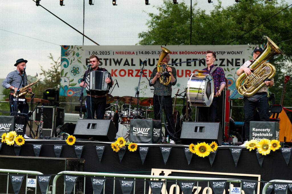 Zdjęcia z Festowalu KOrzenie Europy. Na zdjęciach widoczni są artyści na scenie, prowadzący koncert , publiczność i otoczenie koncertu - Park Bródnowski.