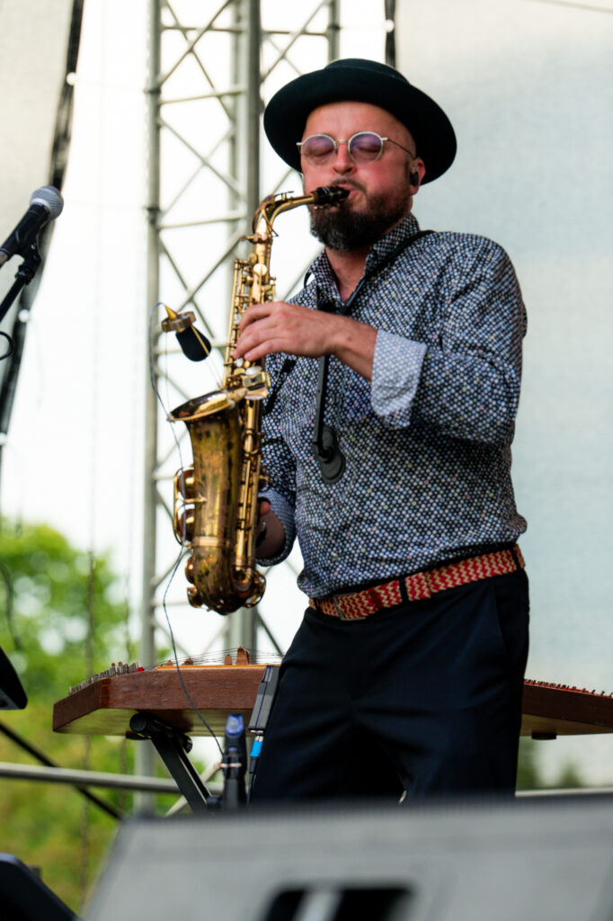 Zdjęcia z Festowalu KOrzenie Europy. Na zdjęciach widoczni są artyści na scenie, prowadzący koncert , publiczność i otoczenie koncertu - Park Bródnowski.