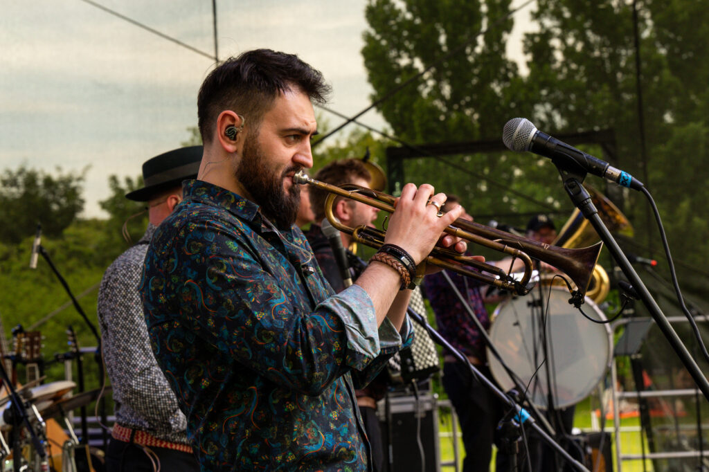Zdjęcia z Festowalu KOrzenie Europy. Na zdjęciach widoczni są artyści na scenie, prowadzący koncert , publiczność i otoczenie koncertu - Park Bródnowski.