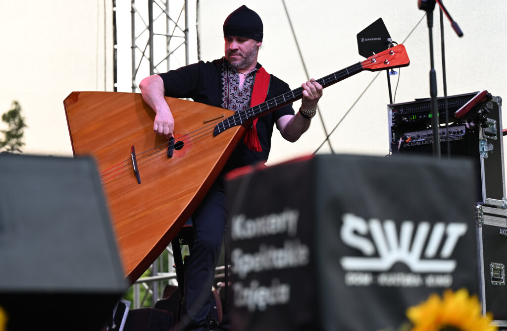 Zdjęcia z Festowalu KOrzenie Europy. Na zdjęciach widoczni są artyści na scenie, prowadzący koncert , publiczność i otoczenie koncertu - Park Bródnowski.