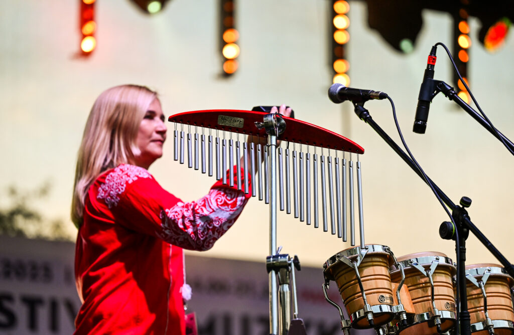 Zdjęcia z Festowalu KOrzenie Europy. Na zdjęciach widoczni są artyści na scenie, prowadzący koncert , publiczność i otoczenie koncertu - Park Bródnowski.