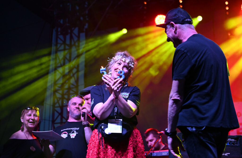 Zdjęcia z Festowalu KOrzenie Europy. Na zdjęciach widoczni są artyści na scenie, prowadzący koncert , publiczność i otoczenie koncertu - Park Bródnowski.