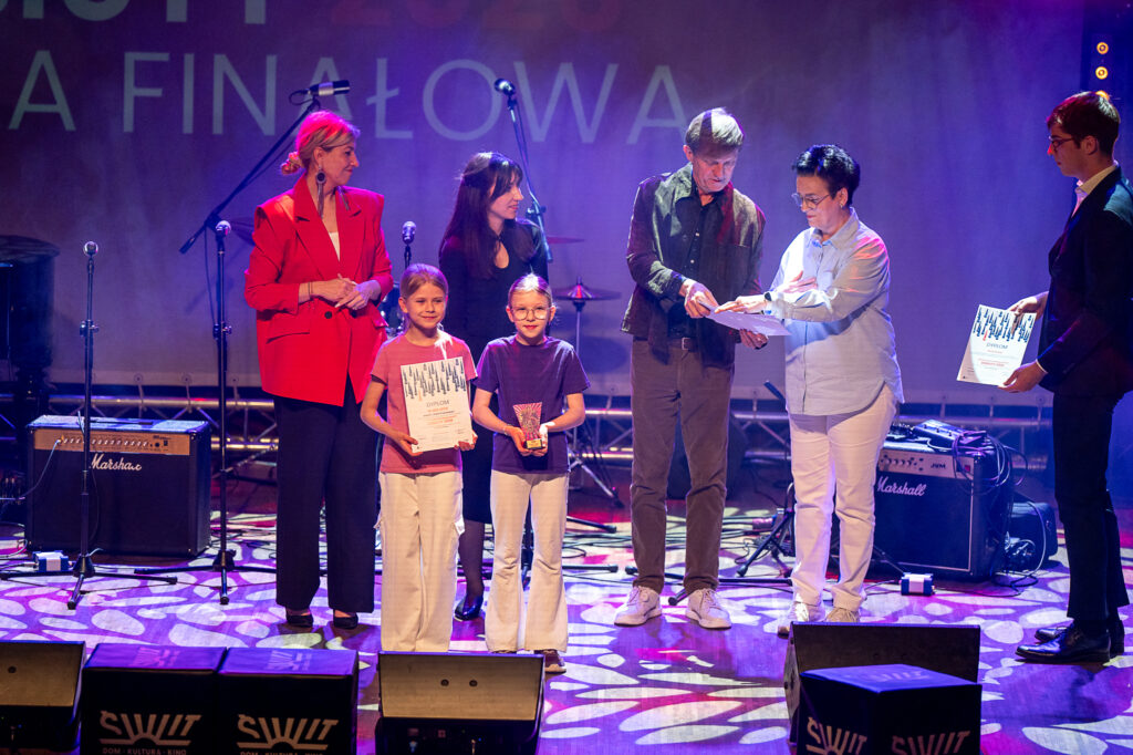 Fotorelacja z Gali Finałowej Konkursu Muzycznego Debiuty 2026. Na oświetlonej, kolorowej scenie wykonawcy: młodzież, i dzieci - soliści i zespoły.
