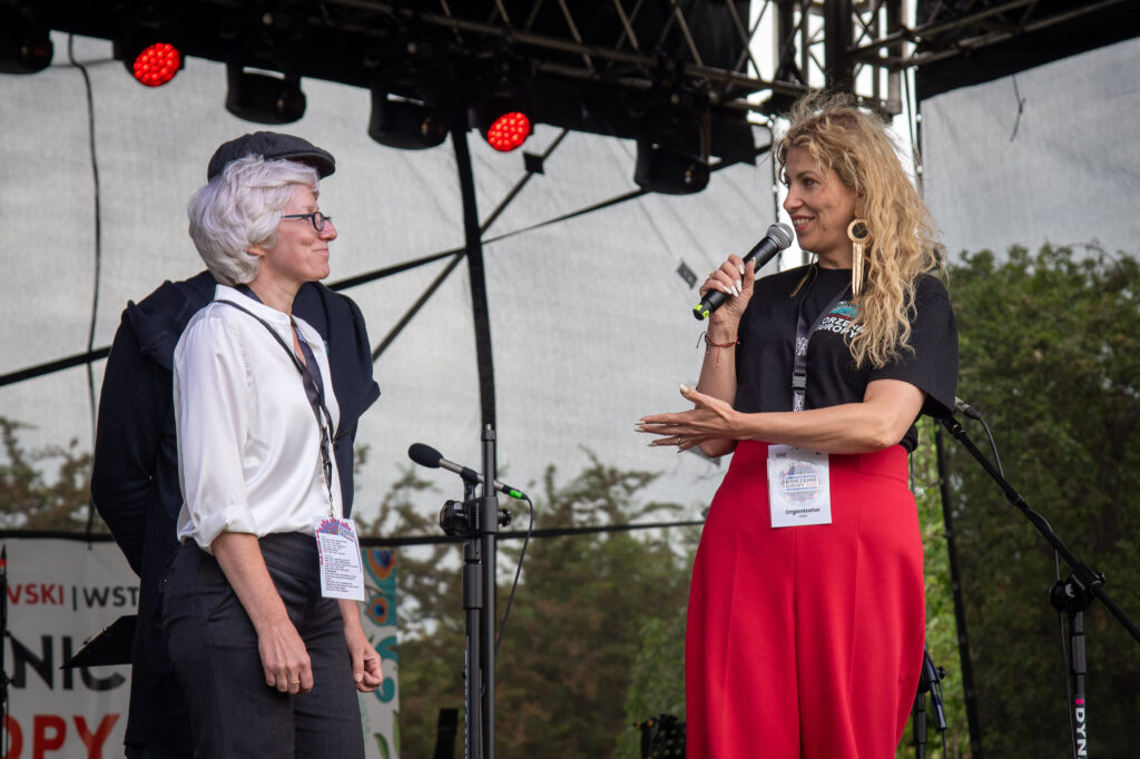 Zdjęcia z XII Festiwalu Muzyki Etnicznej Korzenie Europy, który się odbył 31 maja 2026 r. w Parku Bródnowskich. Na zdjęciach scena plenerowa, zespoły muzyczne, organizatorzy i publiczność w otoczeniu zieleni parku.