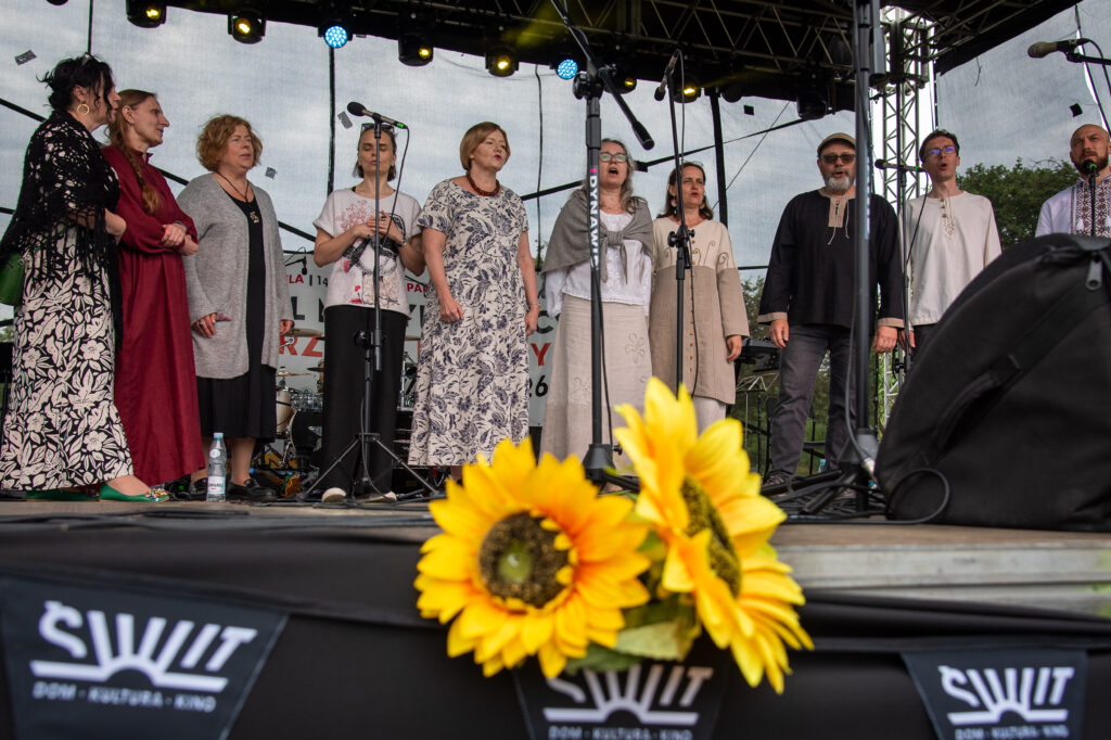 Zdjęcia z XII Festiwalu Muzyki Etnicznej Korzenie Europy, który się odbył 31 maja 2026 r. w Parku Bródnowskich. Na zdjęciach scena plenerowa, zespoły muzyczne, organizatorzy i publiczność w otoczeniu zieleni parku.