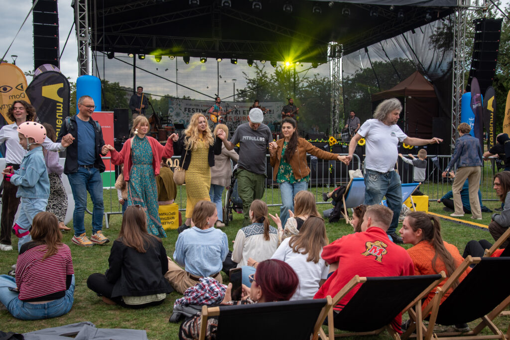 Zdjęcia z XII Festiwalu Muzyki Etnicznej Korzenie Europy, który się odbył 31 maja 2026 r. w Parku Bródnowskich. Na zdjęciach scena plenerowa, zespoły muzyczne, organizatorzy i publiczność w otoczeniu zieleni parku.
