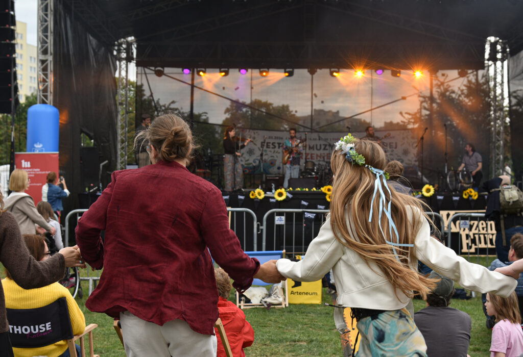 Zdjęcia z XII Festiwalu Muzyki Etnicznej Korzenie Europy, który się odbył 31 maja 2026 r. w Parku Bródnowskich. Na zdjęciach scena plenerowa, zespoły muzyczne, organizatorzy i publiczność w otoczeniu zieleni parku.