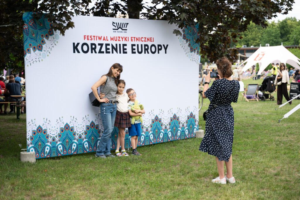 Zdjęcia z XII Festiwalu Muzyki Etnicznej Korzenie Europy, który się odbył 31 maja 2026 r. w Parku Bródnowskich. Na zdjęciach scena plenerowa, zespoły muzyczne, organizatorzy i publiczność w otoczeniu zieleni parku.