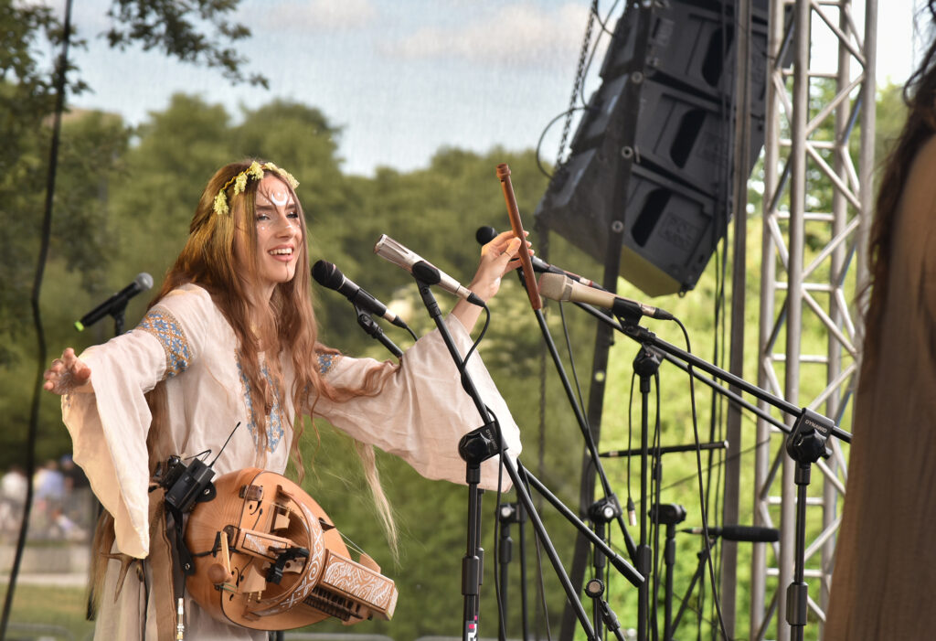 Zdjęcia z XII Festiwalu Muzyki Etnicznej Korzenie Europy, który się odbył 31 maja 2026 r. w Parku Bródnowskich. Na zdjęciach scena plenerowa, zespoły muzyczne, organizatorzy i publiczność w otoczeniu zieleni parku.