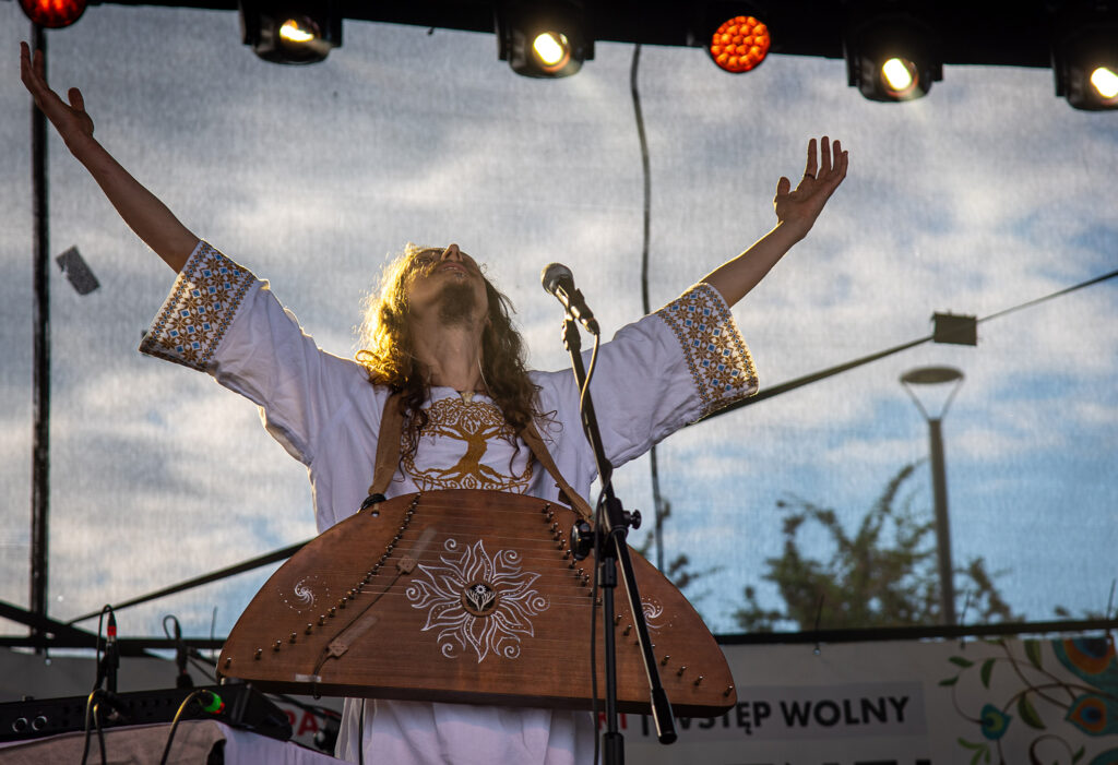Zdjęcia z XII Festiwalu Muzyki Etnicznej Korzenie Europy, który się odbył 31 maja 2026 r. w Parku Bródnowskich. Na zdjęciach scena plenerowa, zespoły muzyczne, organizatorzy i publiczność w otoczeniu zieleni parku.