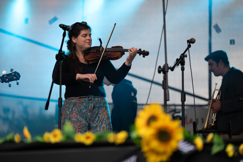 Zdjęcia z XII Festiwalu Muzyki Etnicznej Korzenie Europy, który się odbył 31 maja 2026 r. w Parku Bródnowskich. Na zdjęciach scena plenerowa, zespoły muzyczne, organizatorzy i publiczność w otoczeniu zieleni parku.
