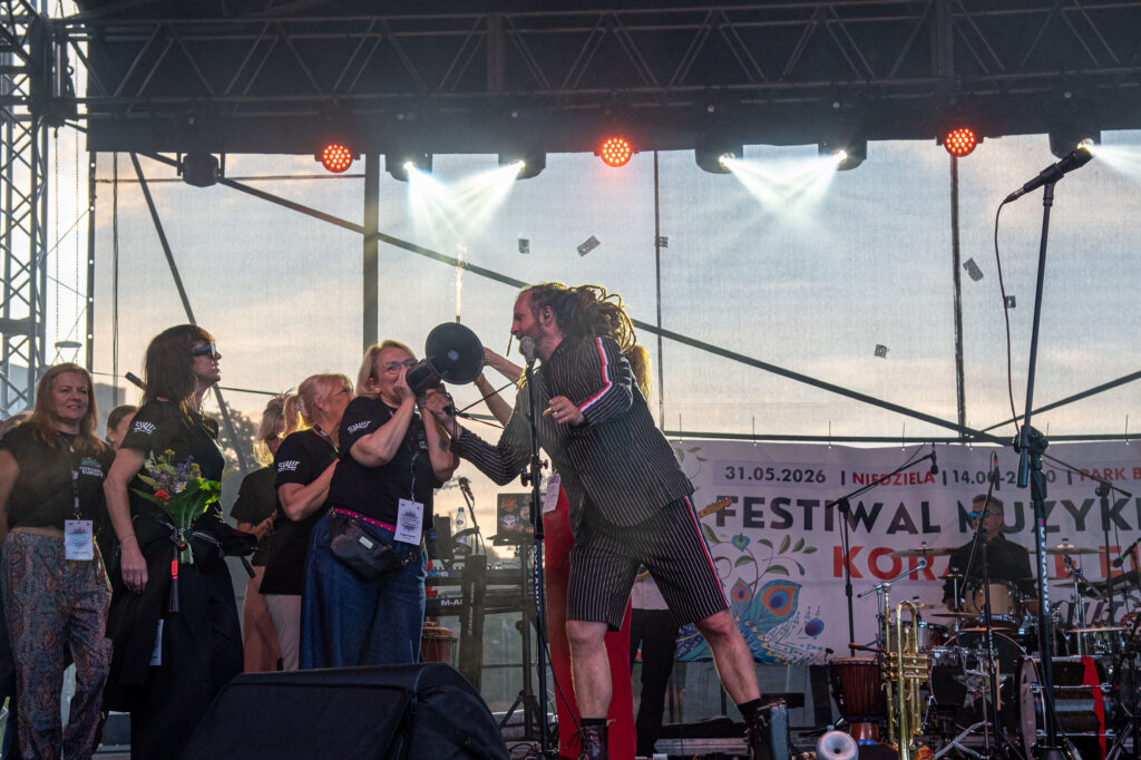 Zdjęcia z XII Festiwalu Muzyki Etnicznej Korzenie Europy, który się odbył 31 maja 2026 r. w Parku Bródnowskich. Na zdjęciach scena plenerowa, zespoły muzyczne, organizatorzy i publiczność w otoczeniu zieleni parku.