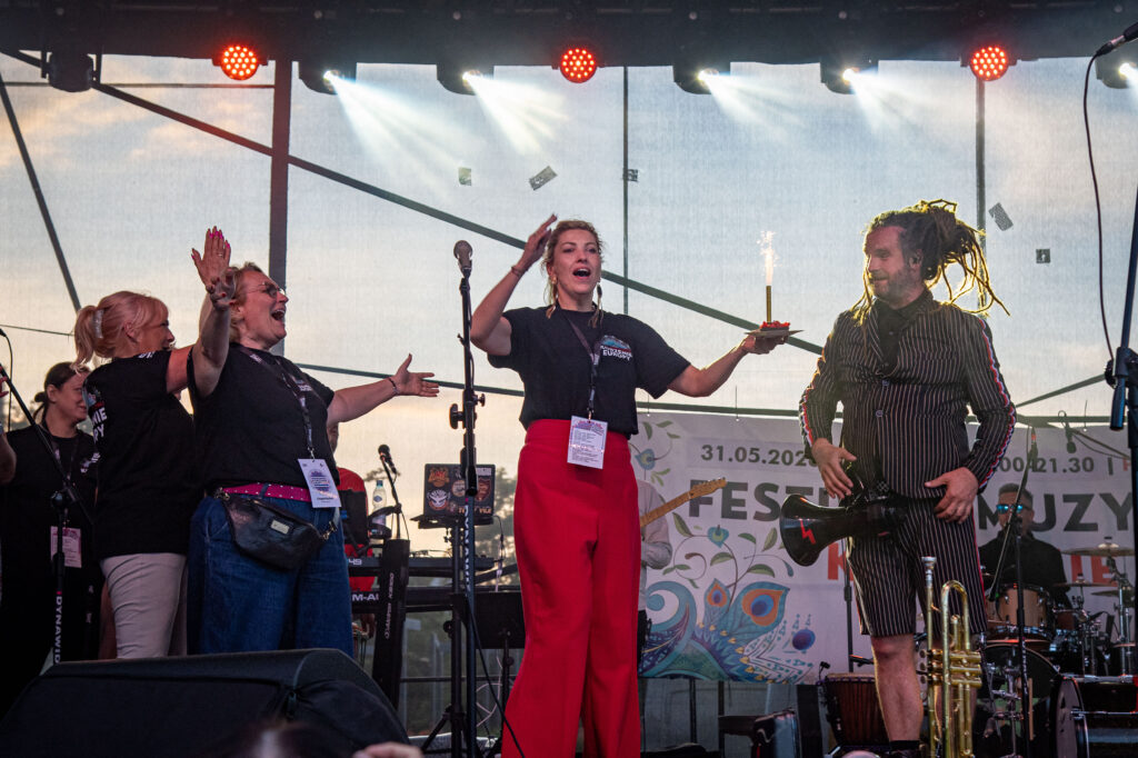 Zdjęcia z XII Festiwalu Muzyki Etnicznej Korzenie Europy, który się odbył 31 maja 2026 r. w Parku Bródnowskich. Na zdjęciach scena plenerowa, zespoły muzyczne, organizatorzy i publiczność w otoczeniu zieleni parku.