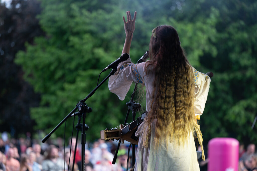 Zdjęcia z XII Festiwalu Muzyki Etnicznej Korzenie Europy, który się odbył 31 maja 2026 r. w Parku Bródnowskich. Na zdjęciach scena plenerowa, zespoły muzyczne, organizatorzy i publiczność w otoczeniu zieleni parku.