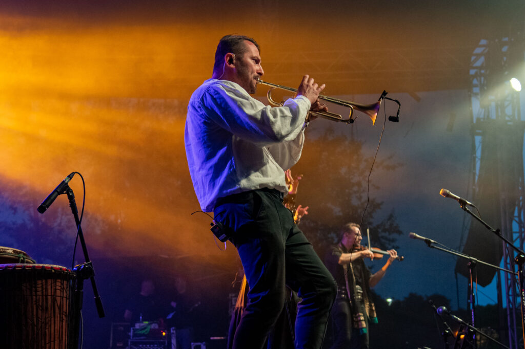 Zdjęcia z XII Festiwalu Muzyki Etnicznej Korzenie Europy, który się odbył 31 maja 2026 r. w Parku Bródnowskich. Na zdjęciach scena plenerowa, zespoły muzyczne, organizatorzy i publiczność w otoczeniu zieleni parku.