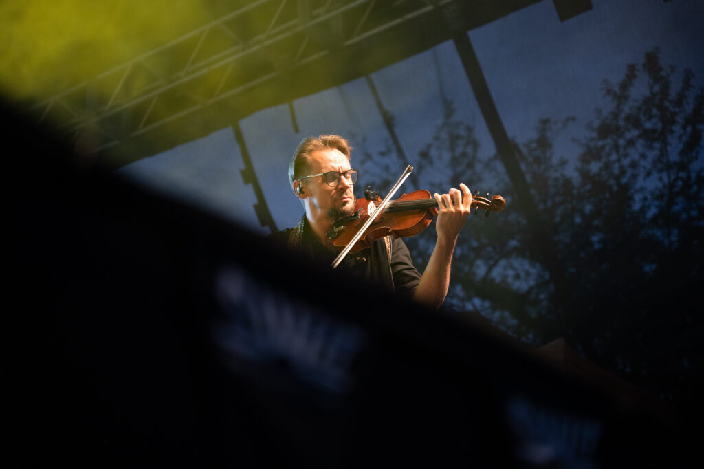 Zdjęcia z XII Festiwalu Muzyki Etnicznej Korzenie Europy, który się odbył 31 maja 2026 r. w Parku Bródnowskich. Na zdjęciach scena plenerowa, zespoły muzyczne, organizatorzy i publiczność w otoczeniu zieleni parku.