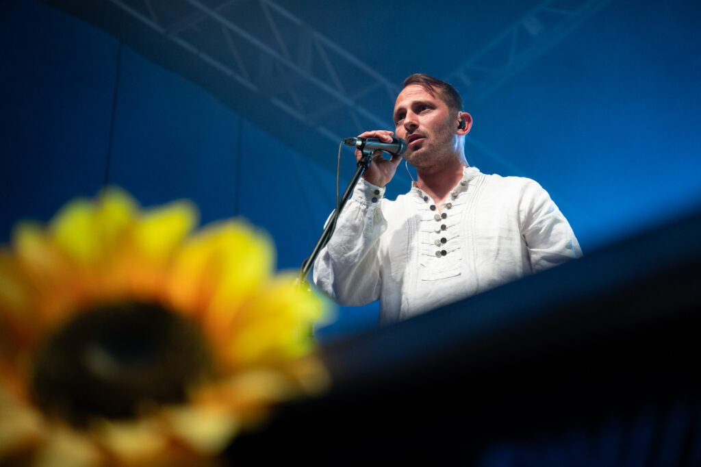 Zdjęcia z XII Festiwalu Muzyki Etnicznej Korzenie Europy, który się odbył 31 maja 2026 r. w Parku Bródnowskich. Na zdjęciach scena plenerowa, zespoły muzyczne, organizatorzy i publiczność w otoczeniu zieleni parku.