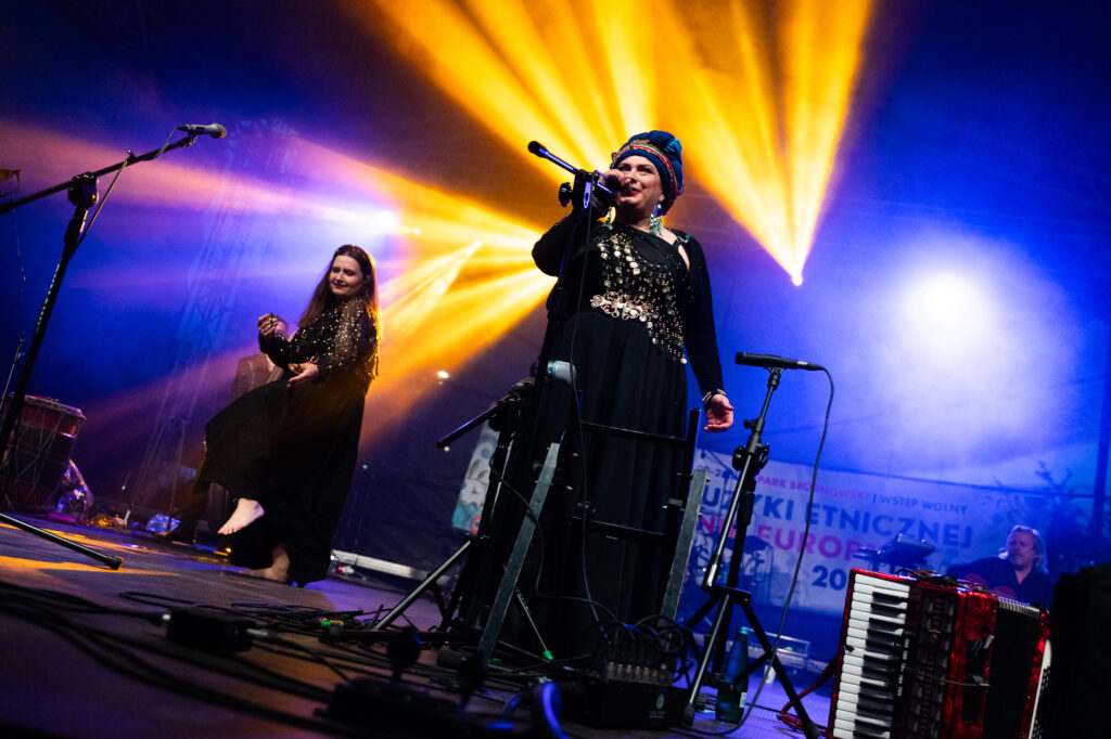Zdjęcia z XII Festiwalu Muzyki Etnicznej Korzenie Europy, który się odbył 31 maja 2026 r. w Parku Bródnowskich. Na zdjęciach scena plenerowa, zespoły muzyczne, organizatorzy i publiczność w otoczeniu zieleni parku.