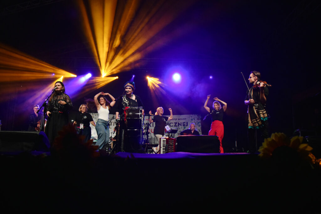 Zdjęcia z XII Festiwalu Muzyki Etnicznej Korzenie Europy, który się odbył 31 maja 2026 r. w Parku Bródnowskich. Na zdjęciach scena plenerowa, zespoły muzyczne, organizatorzy i publiczność w otoczeniu zieleni parku.