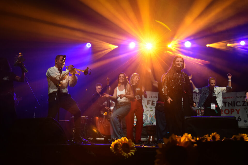Zdjęcia z XII Festiwalu Muzyki Etnicznej Korzenie Europy, który się odbył 31 maja 2026 r. w Parku Bródnowskich. Na zdjęciach scena plenerowa, zespoły muzyczne, organizatorzy i publiczność w otoczeniu zieleni parku.