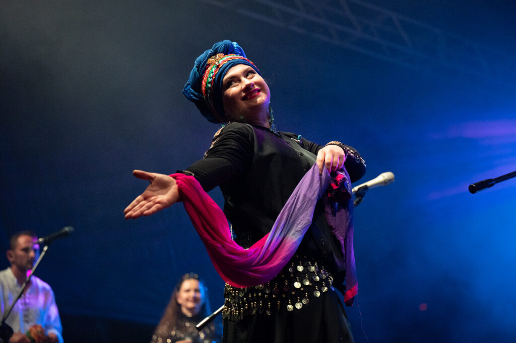 Zdjęcia z XII Festiwalu Muzyki Etnicznej Korzenie Europy, który się odbył 31 maja 2026 r. w Parku Bródnowskich. Na zdjęciach scena plenerowa, zespoły muzyczne, organizatorzy i publiczność w otoczeniu zieleni parku.