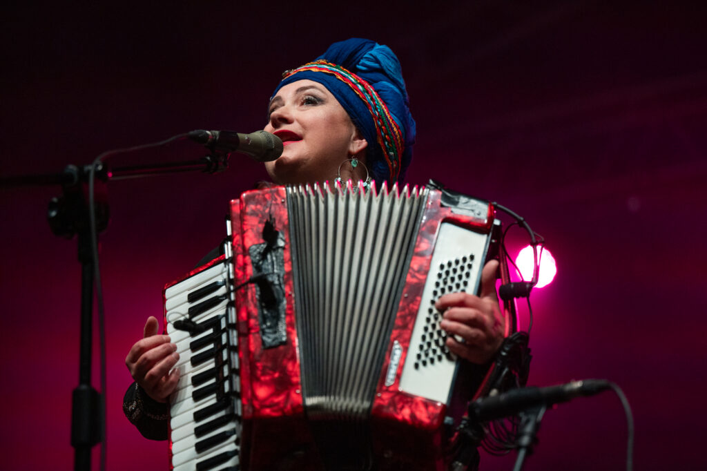 Zdjęcia z XII Festiwalu Muzyki Etnicznej Korzenie Europy, który się odbył 31 maja 2026 r. w Parku Bródnowskich. Na zdjęciach scena plenerowa, zespoły muzyczne, organizatorzy i publiczność w otoczeniu zieleni parku.