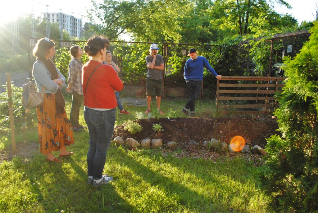 Grupa osób stoi nad pryzmą kompostową.